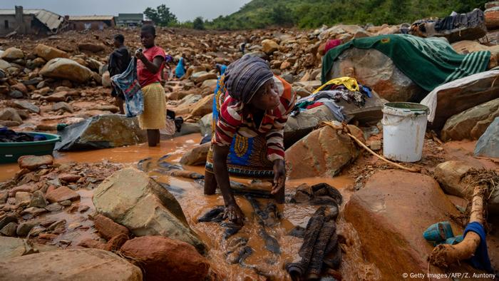 An elderly woman washes her belongings in the mud after Cyclone Idai hit Mozambique