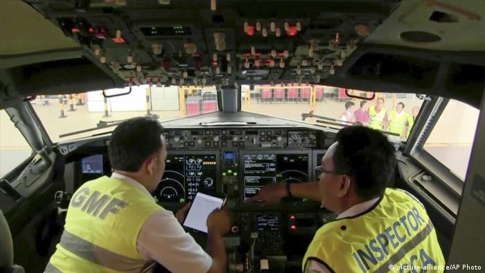 Indonesia inspects look over controls in a 737 cockpit