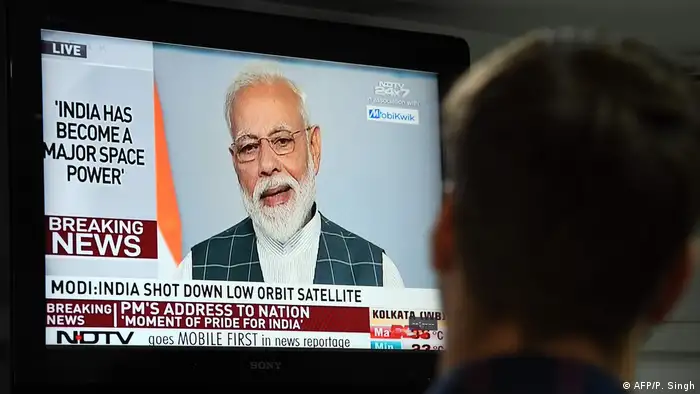 Indian Prime Minister Narendra Modi can be seen on a TV screen talking after India shot down a satellite as part of defense system tests
