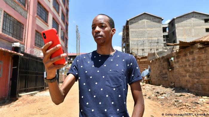 A man in Kenya looks down at his smartphone