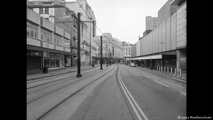 Seemingly black and white photo of an empty street with tram tracks in the middle and a single car parked in the distance (Copyright: Linus Muellerschoen)