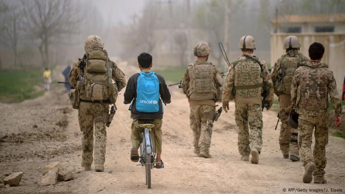 An Afghan boy with an UNICEF schoolbag rides his bicycle past German Soldiers as patrol the area near the DHQ (Char Dara District Police Headquarter) in the province of Kunduz on March 29, 2012