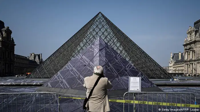 Man takes photo in front of Louvre pyramid