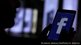 person holding smartphone displaying facebook app