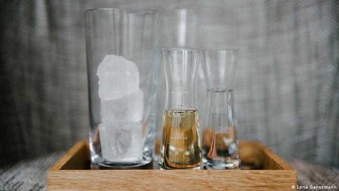 Glass with ice cubes and two glass carafes on wooden tray (Foto: Lena Ganssmann)