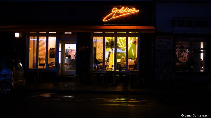 Exterior shot of the restaurant at night with large windows and neon Goldies sign. (Foto: Lena Ganssmann)