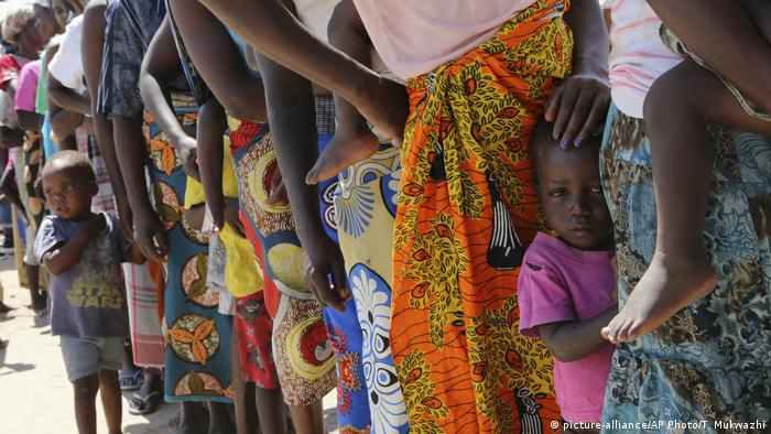Women and children wait in a queue for oral cholera vaccinations, at a camp for displaced survivors