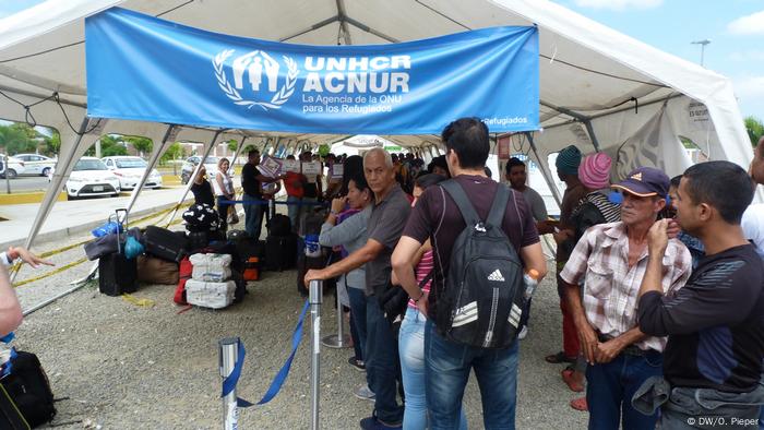 Refugiados venezolanos se encuentran afuera de una carpa humanitaria de ACNUR después de llegar a Tumbes en Perú.