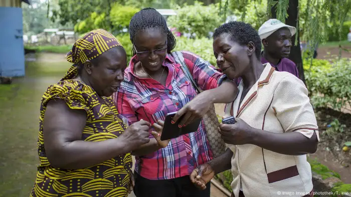 Three women are kooking at a smartphone, one holding another phone in her hand