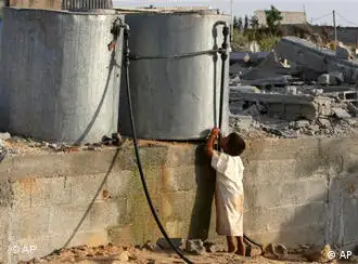 资料图片：一名巴勒斯坦男童在加沙地带被炸毁的房屋废墟中喝水桶里的水