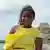 Com vestido amarelo, Yassandra Castro posa em frente a paredão que forma Fortificação de Cartagena em Bocachica, na ilha de Tierra Bomba, na Colômbia