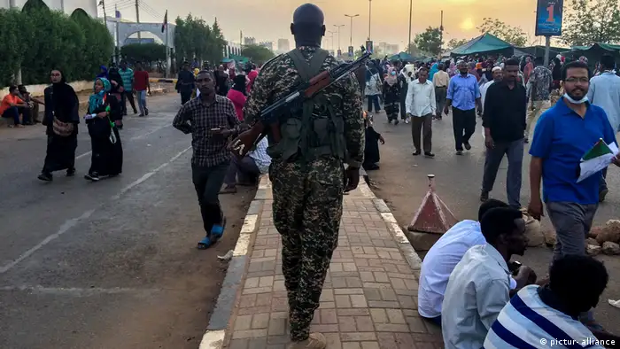 A soldier walks amid protesters in Khartoum, Sudan