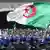 Algerian protesters wave a giant national flag as members of the security forces stand guard during an an anti-government demonstration in the capital Algiers on April 12, 2019
