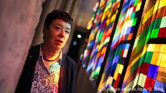Barbara Schock-Werner standing next to the colorful stained-glass window of Cologne cathedral
