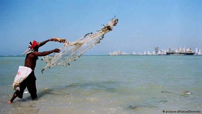 A person throws a fishing net into the sea