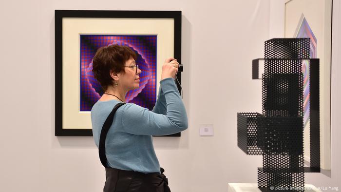 Besucherin fotografiert ein Wandobjekt auf der Art Cologne 2019 (picture-alliance/Xinhua/Lu Yang)