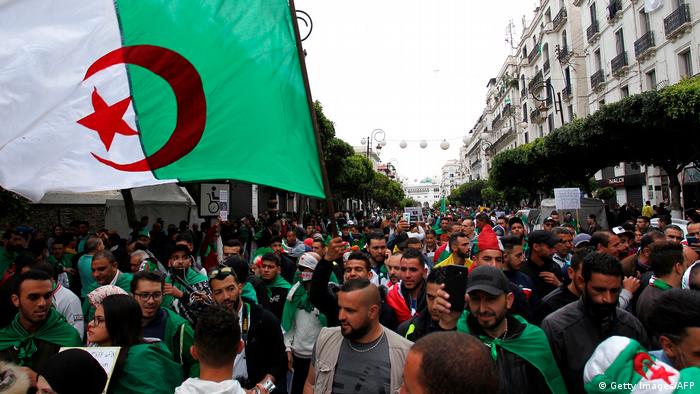 Algerians, draped in national flags, hold banners and chant slogans during an anti government demonstration in the capital Algiers, on April 19, 2019