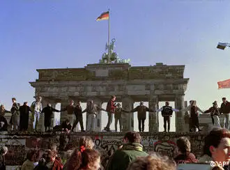 Berliners sing and dance on top of The Berlin Wall to celebrate the opening of East-West German borders
