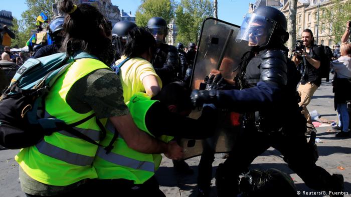 A protester wearing a yellow vest scuffles with a police officer during a demonstration