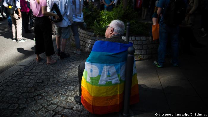 A man wrapped in a Pace flag in Stuttgart (pictzure-alliance/dpa/C. Schmidt)