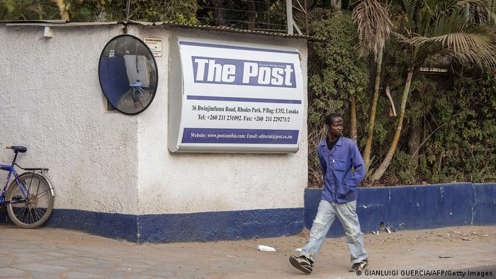 A man walks past a billboard for The Post newspaper