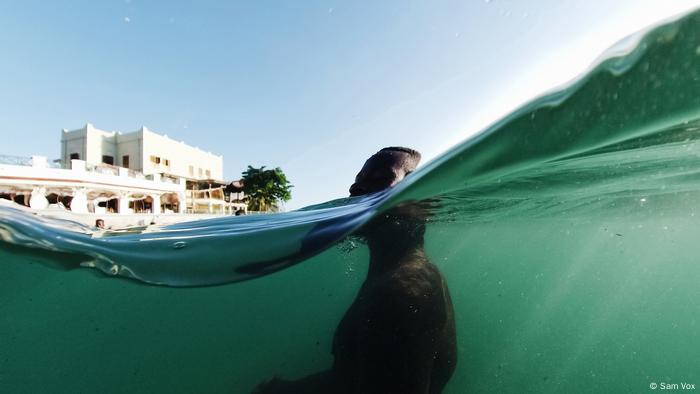 Foto: Floating in Water, Everyday Africa. Ein Mann im Wasser, Kameraperspektive halb im Wasser (Sam Vox)