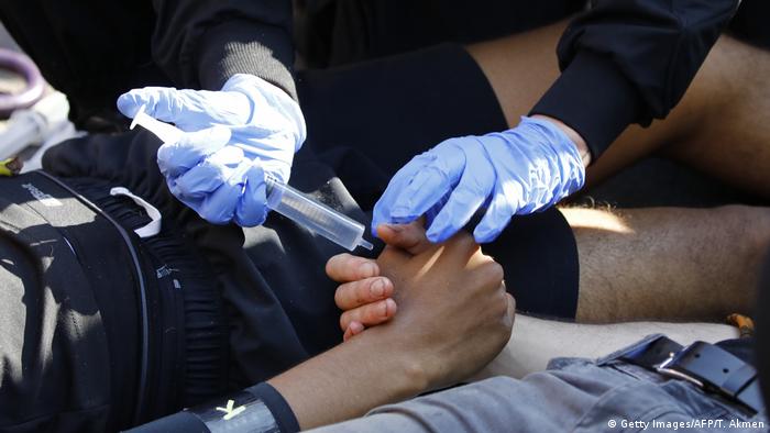Police officers use a solvent to dissolve glue from the hands of climate change activists occupying the road junction at Oxford Circus in central London on April 19, 2019
