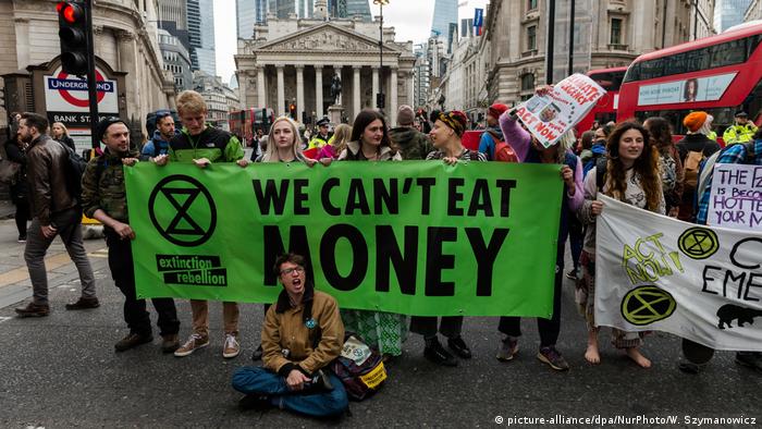 Climate crisis activists block traffic in the London financial district with banners reading Climate Emergency and We Can't Eat Money 
