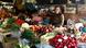 A woman stands behind piles of fruits and vegetables at a market A woman stands behind piles of fruits and vegetables at a market