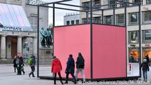 People walking around a pink cube which is the installation Gropius Room Pavilion