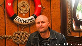 Olaf Sobzcak sitzt in einer typischen alten Eckkneipe. Im Hintergrund eine Rettungsring an der Wand (Foto:Zeitenspiegel, Kathrin Harms)