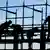A silhouette of four workers on scaffolding in the German city of Frankfurt am Main