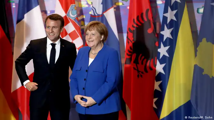 French President Emanuel Macron and German Chancellor Angela Merkel smiling to cameras at the Westbalkan summit of the EU