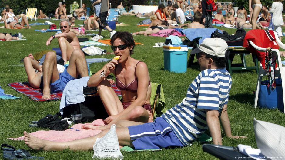 Topless ladies surrounded by dressed men at the beach