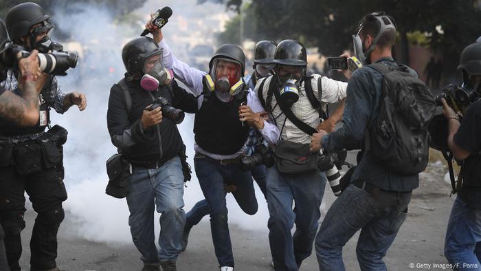 El periodista Gregory Jaimes (centro) es ayudado por colegas durante la represión policial en protestas en Caracas. (2019).