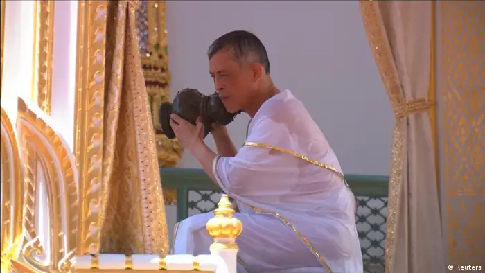 King Maha Vajiralongkorn pouring water over himself (Reuters)