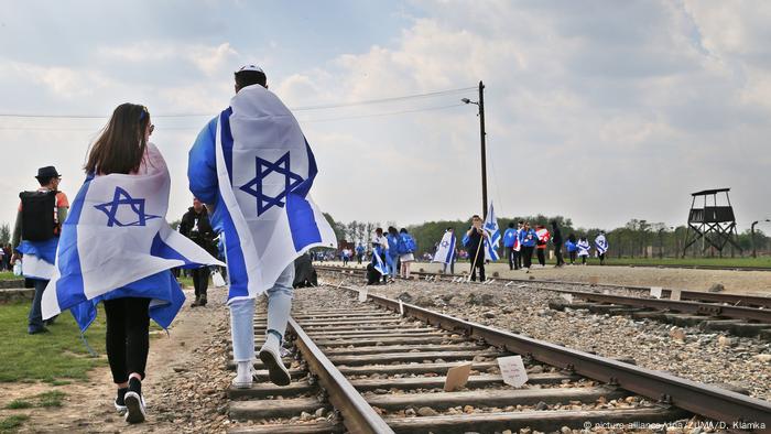 Menschen haben sich in Israel-Flaggen gehüllt und gehen Schienen entlang