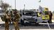 Israeli soldiers gather near a car that was hit by a rocket Israeli soldiers gather near a car that was hit by a rocket