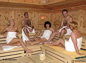 In Handtüchern gewickelte Menschen sitzen in einer Sauna