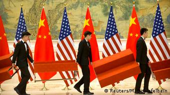 Флаги США и Китая, перед которыми мужчины несут скамейки