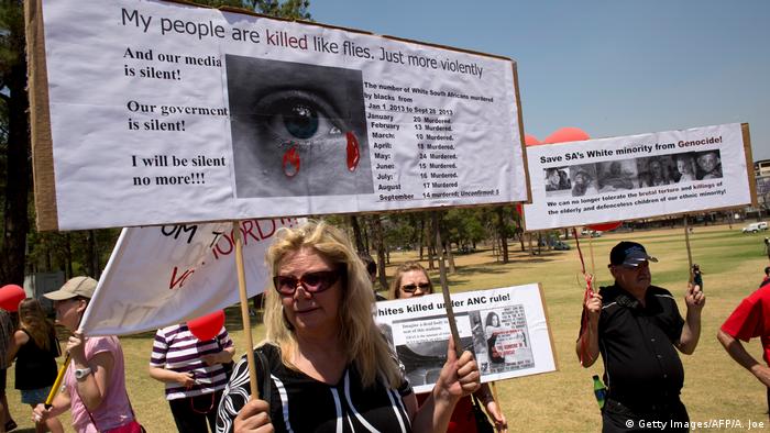 White South Africans hold up placards during a protest against the violent murder of farmers