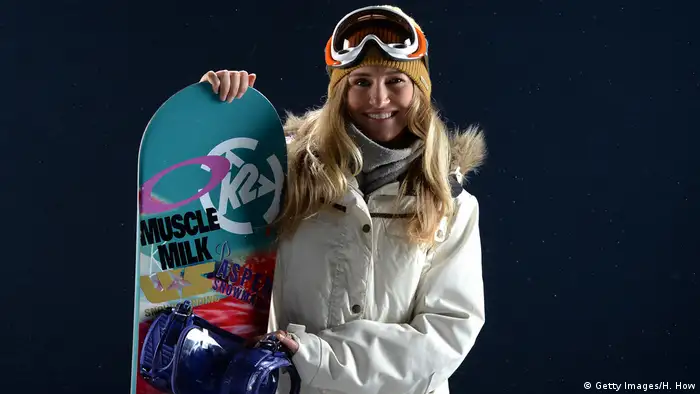 Snowboarder Gretchen Bleiler holds her board and smiles at the camera