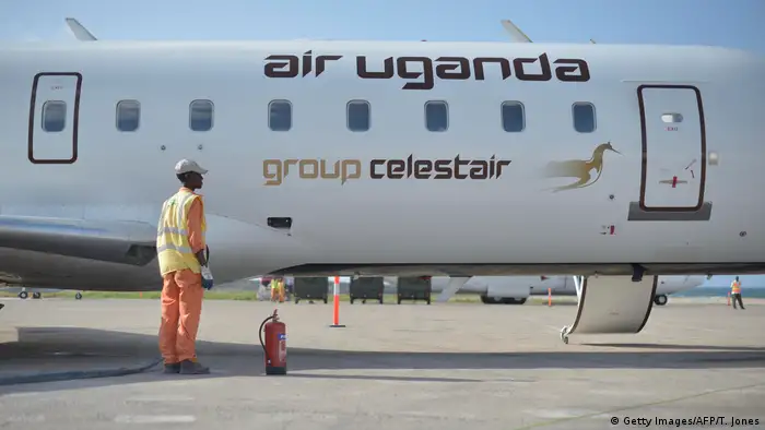 An airport worker stands next to a plane on the tarmac belonging to defunct airline Air Uganda