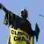 A banner reading 'climate chaos' hangs from a statue during a demonstration against global warming