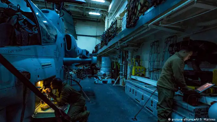 Technicians troubleshoot a night targeting system on an AH-1W Cobra attack helicopter on the flight deck of the USS Arlington