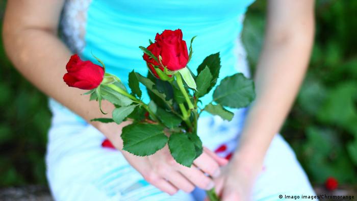 Frau mit Blumenstrauß Muttertag Rote Rosen (Imago images/Chromorange)