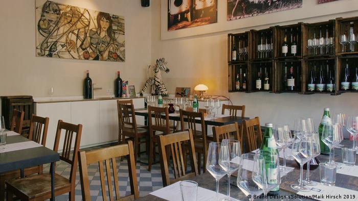 Restaurantaufnahme mit drei gedeckten Tischen, an der Wand ein Weinregal (Foto: Brand Design sSolution/Maik Hirsch 2019).