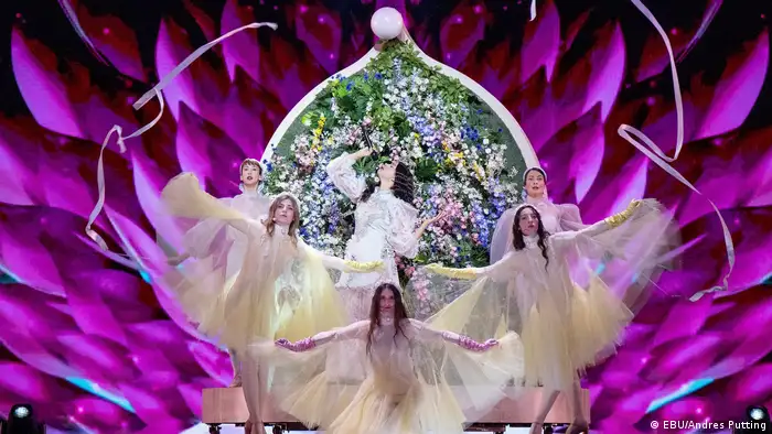 A singer and five ballet dancers in diaphonous gowns backdropped by floral arrangements (EBU/Andres Putting)