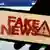 Tela de celular com a frase "Fake news" à frente de uma tela inicial do Facebook