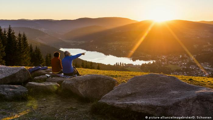 Two people sitting on a rock looking down at Lake Titisee in the Black Forrest